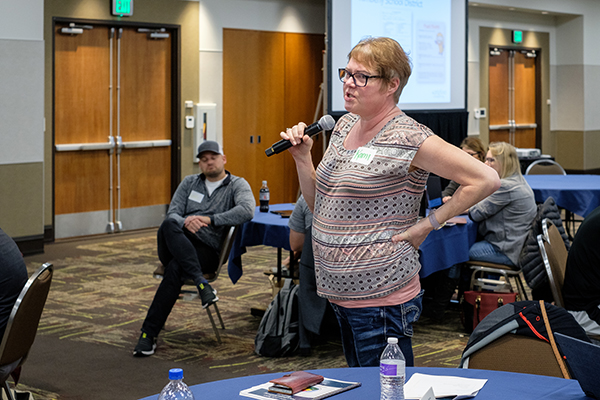 A woman standing and speaking into a microphone during the training. Click to enlarge.