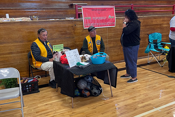 Two men speaking to a woman at a Lions information table. Click to enlarge.